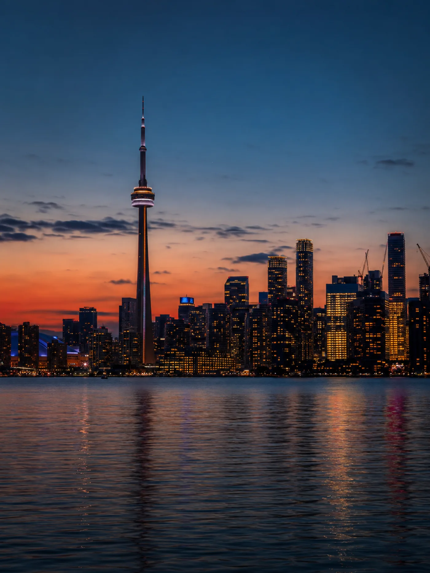 Toronto skyline at twilight with tall observation tower silhouette and warm orange horizon reflecting on Lake Ontario - Ontario High 5 Casino player base